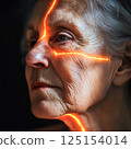 Elderly woman with glowing lines on face and reflective look, undergoing medical examination with laser, magnetic resonance therapy 125154014