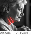 Elderly female experiencing neck pain with red light highlight 125154016