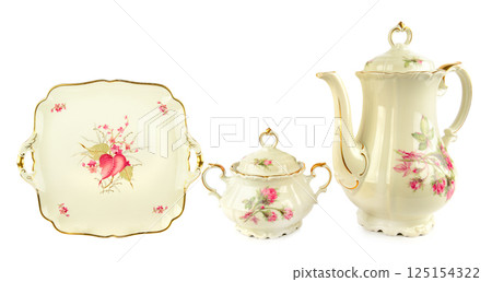 Elegant vintage porcelain coffee pot, porcelain sugar bowl and Vintage plate of unusual shape with gold rim isolated on white background. Elegant vintage porcelain coffee pot, porcelain sugar bowl and Vintage plate of unusual shape with gold rim isolated on white background. 125154322