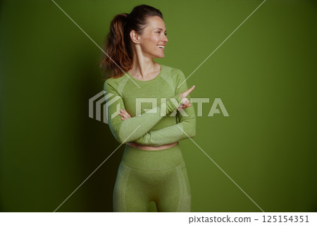 Fit woman in green pointing to the side 125154351