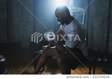 Fitness workout in gym. African American man bodybuilder picking up dumbbells in gym. Workout weight training biceps muscles with dumbbell in fitness club. Man doing sports exercise. Healthy lifestyle Fitness workout in gym. African American man bodybuilder picking up dumbbells in gym. Workout weight training biceps muscles with dumbbell in fitness club. Man doing sports exercise. Healthy lifestyle 125154520
