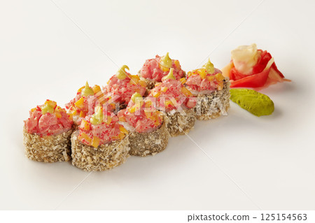 Tempura sushi rolls with spicy tuna, mango, and tobiko, featuring wasabi and ginger 125154563