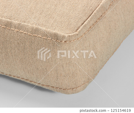 Corner of beige canvas cushion showing stitching detail 125154619