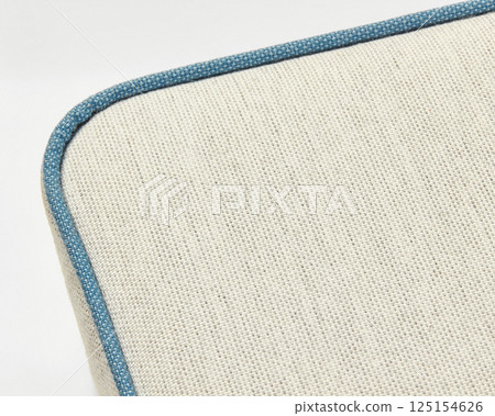 Beige linen upholstery with blue piping creates a textured surface 125154626