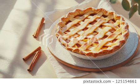 Freshly baked apple tart with cinnamon, walnuts, and golden crust. Styled in soft natural light on a rustic wooden table. Ideal for seasonal baking and holiday visuals. 125154661