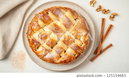 Top-down view of homemade apple pie with spiced filling and flaky crust. Warm tones, cozy textures, and vintage kitchen elements enhance the comforting mood of this dessert shot. 125154663