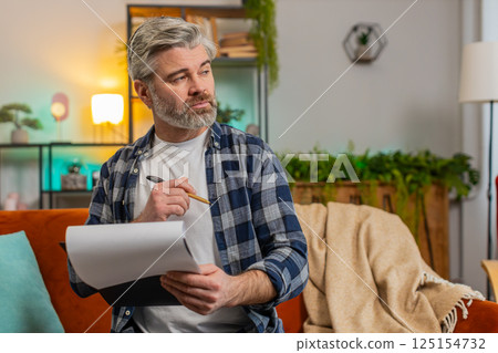 Mature man with documents analyzing information reading business papers prepare financial report 125154732