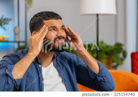 Sick ill Indian man rubbing temples to cure headache problem suffering from tension migraine stress 125154740