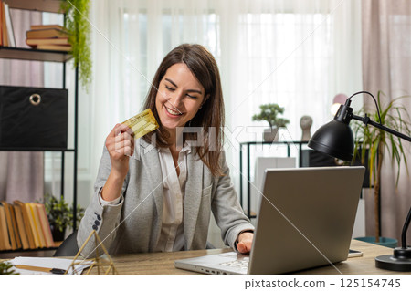 Business woman using bank credit card and laptop for online shopping bill payments at home office Business woman using bank credit card and laptop for online shopping bill payments at home office 125154745