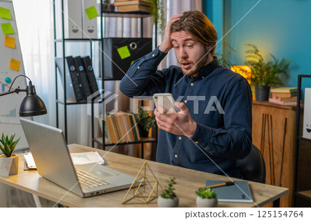 Business man using smartphone bad news lottery game results fortune loss fail at home office 125154764