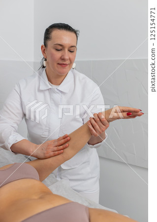 Cosmetologist massagist making woman treatment massage scrubbing hand with scrub in spa clinic 125154771