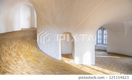 The spiral ramp of the Round Tower invites visitors to ascend through its elegant curves, showcasing a stunning brick floor and soft natural light streaming through arched windows. 125154823