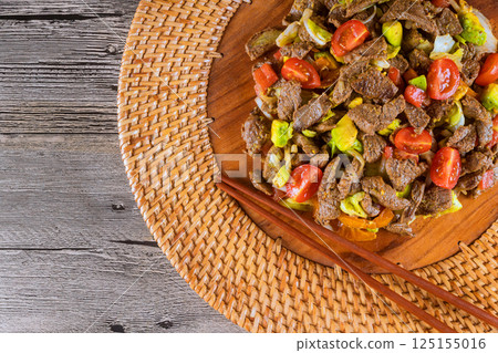 Sizzling beef strips mixed with Asian cuisine tasty vegetables create mouthwatering dish on rustic wooden platter. Sizzling beef strips mixed with Asian cuisine tasty vegetables create mouthwatering dish on rustic wooden platter. 125155016