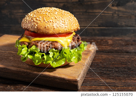 Homemade burger, cheeseburger on dark wooden background Homemade burger, cheeseburger on dark wooden background 125155070