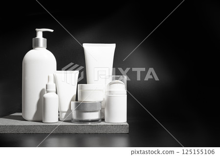 Cosmetic products containers on stone podium and black background 125155106