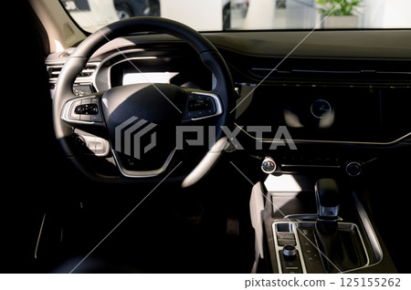 Black steering wheel, automatic transmission,control display in a modern car. 125155262