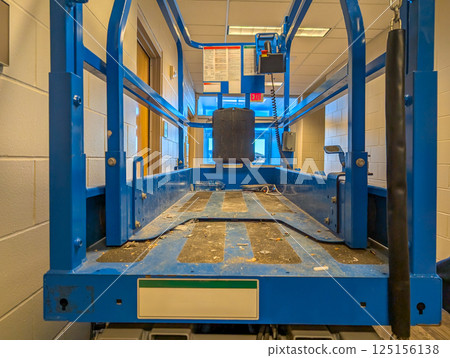 open gate to a scissor lift lowered inside a building construction project.  125156138