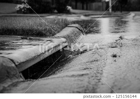 Stormwater flowing into street intake drain after a rainstorm 125156144