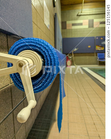 Indoor plastic floating pool cover retracted on a reel. Indoor plastic floating pool cover retracted on a reel. 125156145