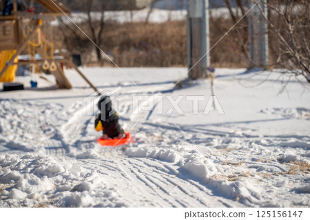 Selective focus on the snow path on the top of a hill with a child sledding down in a backyard  125156147