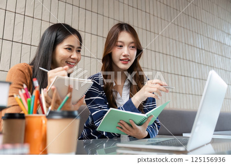Group Study and Discussion. Two friends collaborating over study materials on a laptop. Group Study and Discussion. Two friends collaborating over study materials on a laptop. 125156936