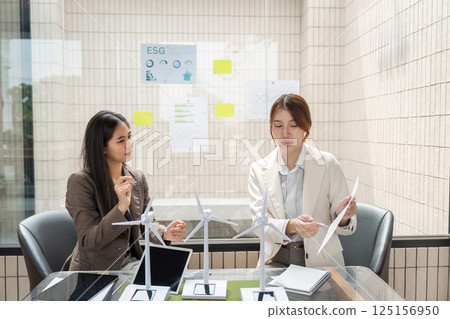 ESG and Sustainable Development. Two professionals discuss renewable energy solutions in a modern office setting. ESG and Sustainable Development. Two professionals discuss renewable energy solutions in a modern office setting. 125156950
