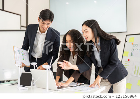 ESG Strategies and Team Engagement. Professionals discussing sustainable development using a laptop. 125156964