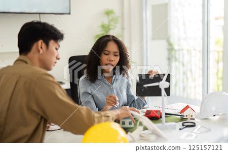 Eco-friendly Energy Solutions and Professional Collaboration. Engaged individuals discuss sustainable design strategies. 125157121