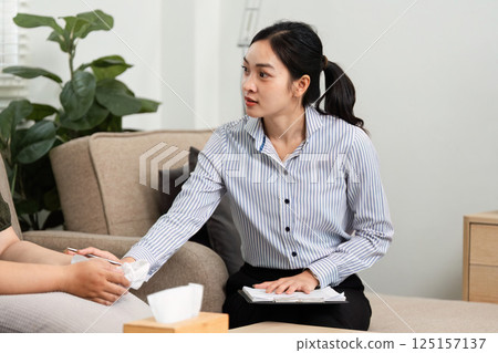 Psychiatric Consultation and Support. A psychiatrist engaging in a compassionate discussion with a client in a comfortable setting. 125157137