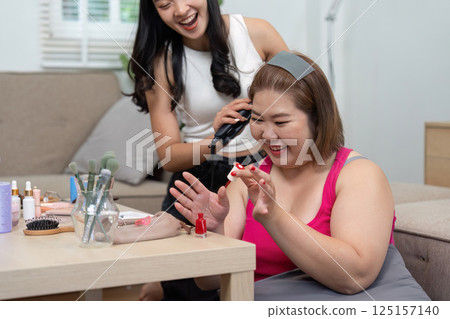Beauty and Friendship. Two women enjoying a fun makeup session together in a cozy setting. 125157140