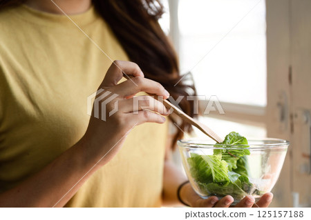 Healthy Eating and Mindful Living. A woman preparing to enjoy her fresh salad in a sunlit kitchen. Healthy Eating and Mindful Living. A woman preparing to enjoy her fresh salad in a sunlit kitchen. 125157188