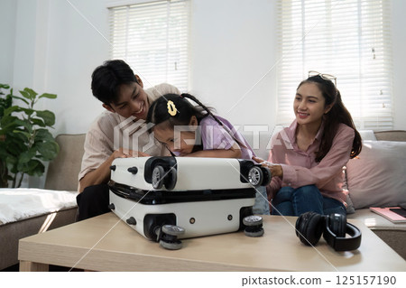 Family Interaction and Child's Joy. A girl and her parents enjoy a fun moment with a suitcase. 125157190
