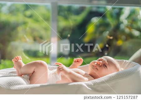 Newborn baby comfortably resting in a cozy baby nest. Safe and peaceful sleep concept for infants 125157287