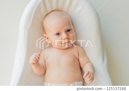 Newborn baby comfortably resting in a cozy baby nest. Safe and peaceful sleep concept for infants Newborn baby comfortably resting in a cozy baby nest. Safe and peaceful sleep concept for infants 125157288