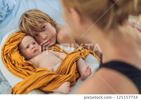 Older brother hugging his newborn sibling. Heartwarming family moment, love, and bonding between siblings. Childhood memories and family connection concept Older brother hugging his newborn sibling. Heartwarming family moment, love, and bonding between siblings. Childhood memories and family connection concept 125157734