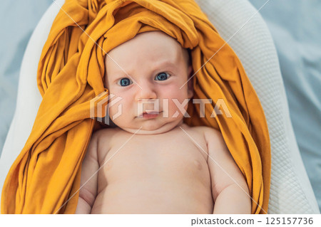 Newborn baby comfortably resting in a cozy baby nest. Safe and peaceful sleep concept for infants Newborn baby comfortably resting in a cozy baby nest. Safe and peaceful sleep concept for infants 125157736