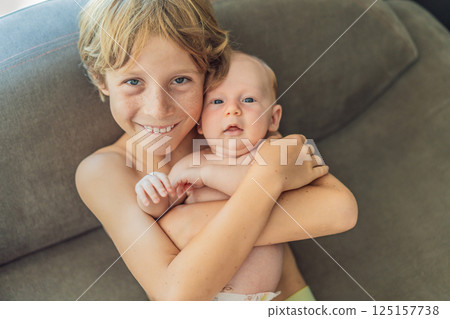 Older brother hugging his newborn sibling. Heartwarming family moment, love, and bonding between siblings. Childhood memories and family connection concept Older brother hugging his newborn sibling. Heartwarming family moment, love, and bonding between siblings. Childhood memories and family connection concept 125157738