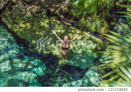 Female tourist enjoying a refreshing swim in a Mexican cenote with turquoise water. Adventure, travel, and nature exploration concept Female tourist enjoying a refreshing swim in a Mexican cenote with turquoise water. Adventure, travel, and nature exploration concept 125158685