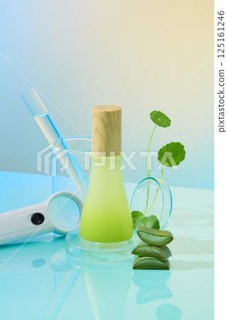 Gradient green glass jar with cylindrical wooden lid. Magnifying glass with plastic handle. Glass jar containing test tubes. Gotu kola with soft stem and aloe vera cut into pieces to reveal flesh. 125161246
