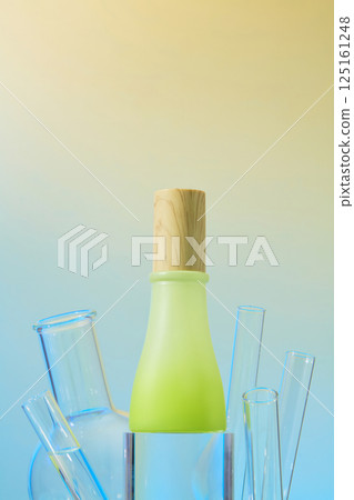 Unlabeled serum bottle with cylindrical wooden stopper, displayed on a glass pedestal. Clear glass test tubes stand upright like thorns. Blue and orange gradient background. Advertising photo. 125161248