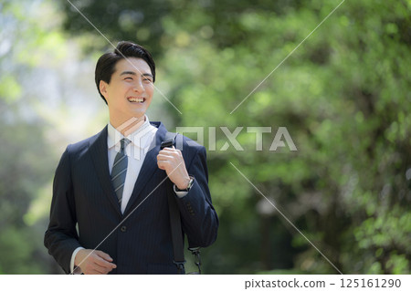 A businessman in a suit looking up outdoors with a fresh green background A businessman in a suit looking up outdoors with a fresh green background 125161290
