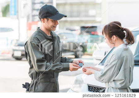 A male auto mechanic staff member taking car keys from a female customer A male auto mechanic staff member taking car keys from a female customer 125161829