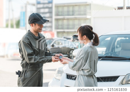 一名男汽車修理工從一名女顧客手中拿走車鑰匙 125161830