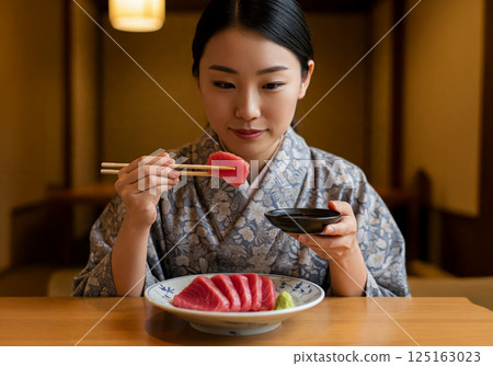 A woman in a kimono eating sashimi A woman in a kimono eating sashimi 125163023