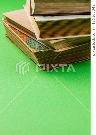 Stack of vintage books resting on green background in a cozy atmosphere 125163342