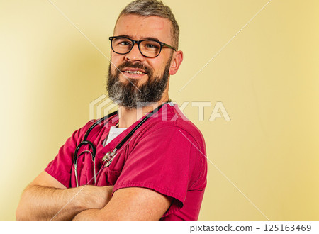 Caring male doctor in scrubs smiling confidently in a clinic setting Caring male doctor in scrubs smiling confidently in a clinic setting 125163469