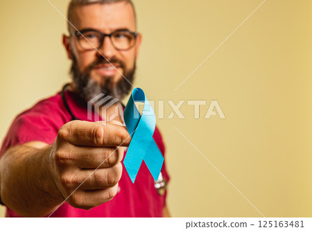 Medical professional highlights awareness with blue ribbon in clinic setting Medical professional highlights awareness with blue ribbon in clinic setting 125163481