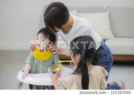 Family giving baby food and milk to a baby 125163566