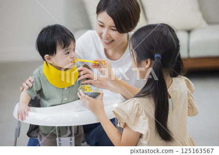Family giving baby food and milk to a baby 125163567