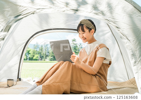 Girl using a tablet in a tent at a campsite/leisure facility 125163608